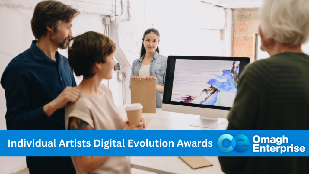 3 people standing round a MAC computer, with another person in the background. The 3 people are admiring a digital art rendition of abstract blue art on the monitor. Blue banner across the bottom. White text - "Individual Artists Digital Evolution Awards" Omagh Enterprise logo within the banner.