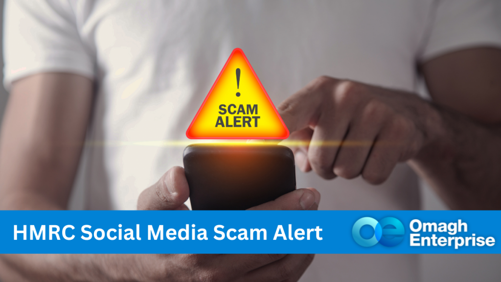 A close up of a person's body, holding a mobile phone and operating it with one finger. A glowing yellow triangle, with a red border is above the phone. Text within the triangle "! SCAM ALERT" A blue banner along the bottom of the screen. White text - "HMRC Social Media Scam Alert" Omagh Enterprise logo within the banner.