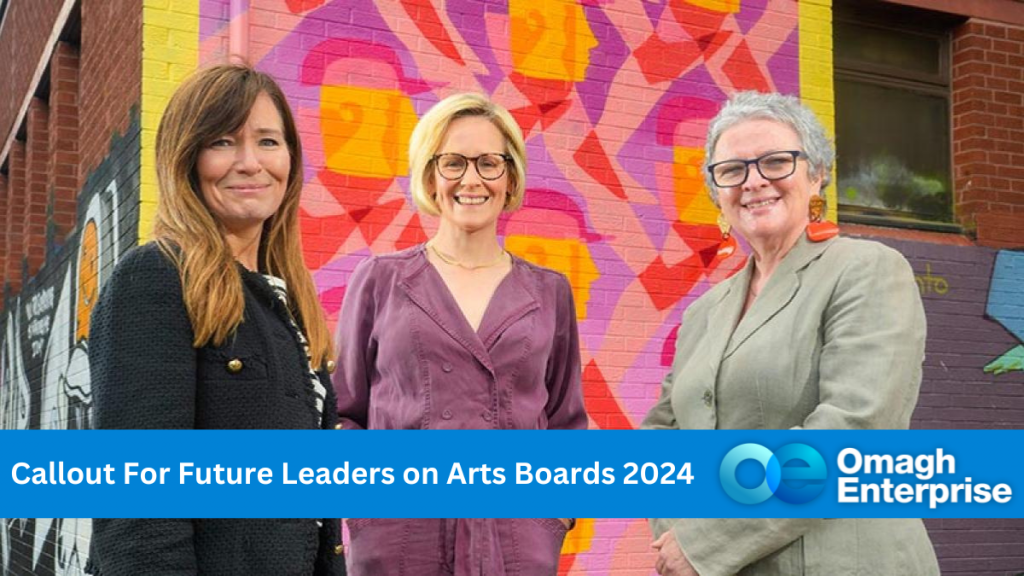 Three women standing in front of a mural wall, made up of purple and pink swirl colours. Blue banner along the bottom with white text "Callout For Future Leaders on Arts Boards 2024" Omagh Enterprise logo within the banner.