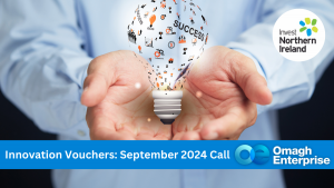 A close up of someone hand's, cupping a suspended light blub. On the surface of the bulb are various innovation symbols. The world "success" is also on the bulb. Blue banner along the bottom of the image, with white text. "Innovation Vouchers: September 2024 Call" Omagh Enterprise logo is within the banner.