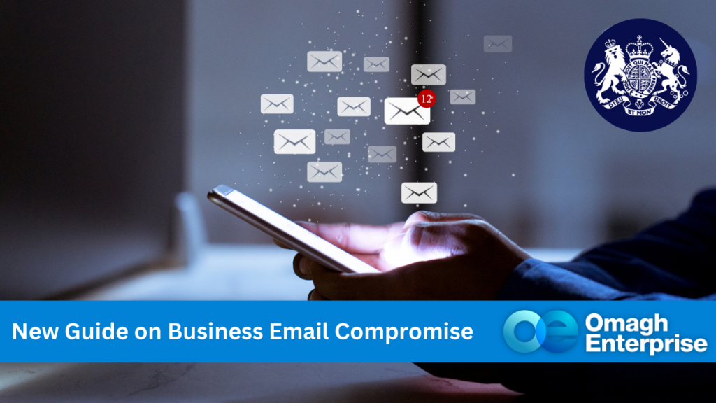 A hand holding a mobile phone in the dark, with the screen glowing. Email icons are radiating from the phone. Blue banner along the bottom, with white text. "New Guide on Business Email Compromise" Omagh Enterprise logo within the banner.