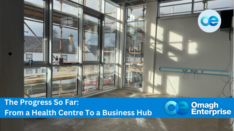 A room under construction with large windows letting in natural light. Scaffolding is visible outside. Text overlay reads The Progress So Far: From a Health Centre To a Business Hub with Omagh Enterprise logo in the bottom right corner.