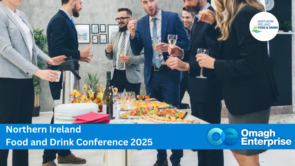 A group of people in business attire socialize at the Northern Ireland Food and Drink Conference 2025. They stand around a table with food and drinks. Logos for Northern Ireland Food and Drink and Omagh Enterprise appear prominently.