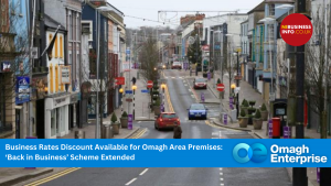 A quiet street in Omagh town with a few cars and pedestrians; banners and business rates discount information appear in the foreground.