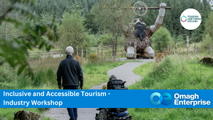 A paved path leads to a wooden sculpture in a forest. A person in a wheelchair and another walking are on the path, with an "Inclusive and Accessible Tourism" workshop banner.