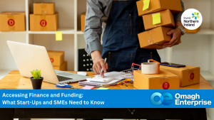 Person in an apron holding boxes and using a calculator at a desk with packaging supplies; text overlay discusses finance for start-ups and SMEs, branded with Omagh Enterprise and Invest Northern Ireland.