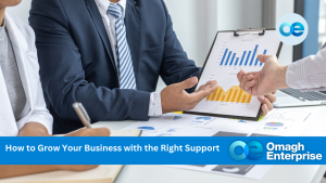 Two business professionals review charts and graphs on paper and a clipboard during a meeting, with Omagh Enterprise branding and a banner reading, "How to Grow Your Business with the Right Support.