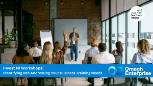 A group of people attend a business workshop, with a presenter standing at the front and a participant raising their hand. Invest NI and Omagh Enterprise branding are visible.