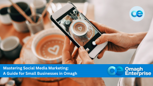 A person takes a photo of a decorated cake with a smartphone. Text overlay promotes a social media marketing guide for small businesses in Omagh by Omagh Enterprise.