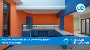 Modern office kitchen area with orange and blue walls, countertops, and cabinets. Overlay text reads: "How to Choose the Best Co-Working Space for Your Business - Omagh Enterprise.