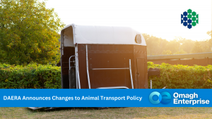 A horse trailer stands by a hedge in sunlight. A banner reads, "DAERA Announces Changes to Animal Transport Policy – Omagh Enterprise.