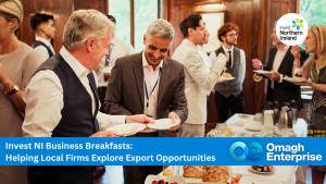 Business professionals networking and enjoying breakfast at an Invest NI event, with a banner promoting export opportunities for local firms hosted by Omagh Enterprise.