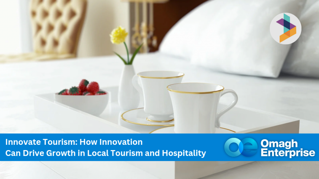 A white tray with two teacups, a teapot, and a bowl of strawberries on a neatly made bed; promotional banner for Omagh Enterprise’s tourism innovation event.