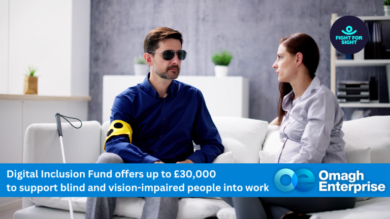 A man with a white cane and vision impairment sits on a couch talking to a woman; a banner promotes Omagh Enterprise’s Digital Inclusion Fund for blind and vision-impaired employment support.