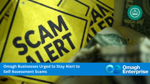 Yellow "SCAM ALERT" signs with blurred currency notes; banner warns Omagh businesses to be cautious of self-assessment scams, branded by Omagh Enterprise.