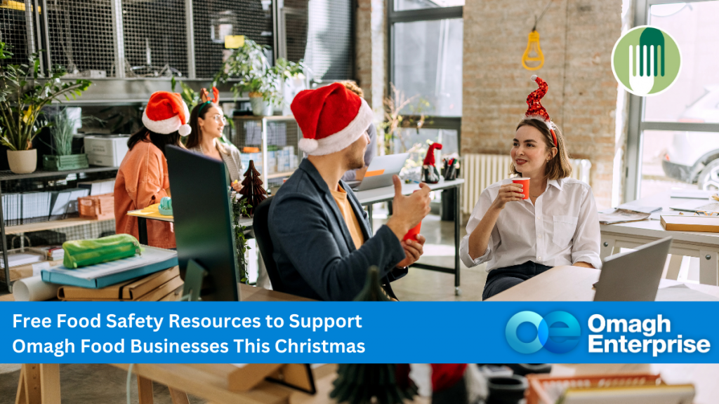 Office workers wearing Santa hats sit at desks, drinking and talking, with Christmas decorations around. A banner promotes free food safety resources for Omagh food businesses at Christmas.