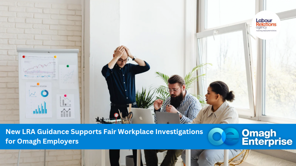 Three people sit around a desk with laptops and papers, discussing work in a bright office. One person stands, holding their head in frustration. Charts and graphs are displayed on the wall. A banner reads, Omagh Enterprise.