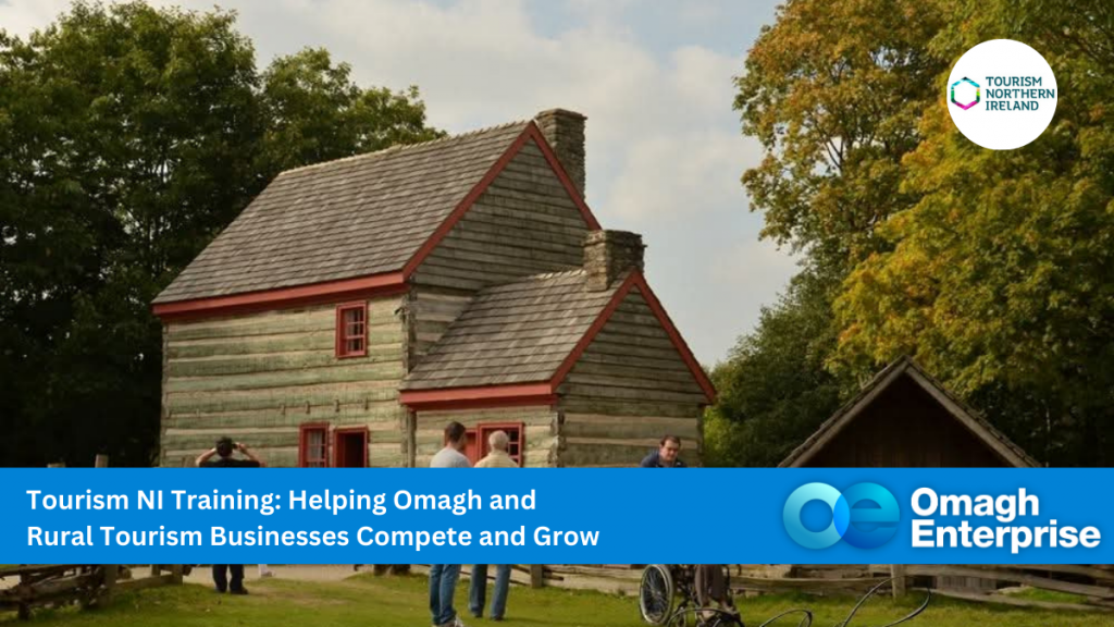 A group of people gather outside a rustic wooden cottage at the Ulster-American Folk Park in Omagh, surrounded by trees. Text overlay promotes Tourism NI training for Omagh and rural tourism businesses, featuring the Tourism Northern Ireland and Omagh Enterprise logos.