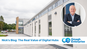 Sideways view of the front of the modern Digi-Hub building with large windows, featuring a circular inset photo of Nick smiling in a suit. Text reads: "Nick's Blog: The Real Value of Digital Hubs, Omagh Enterprise.