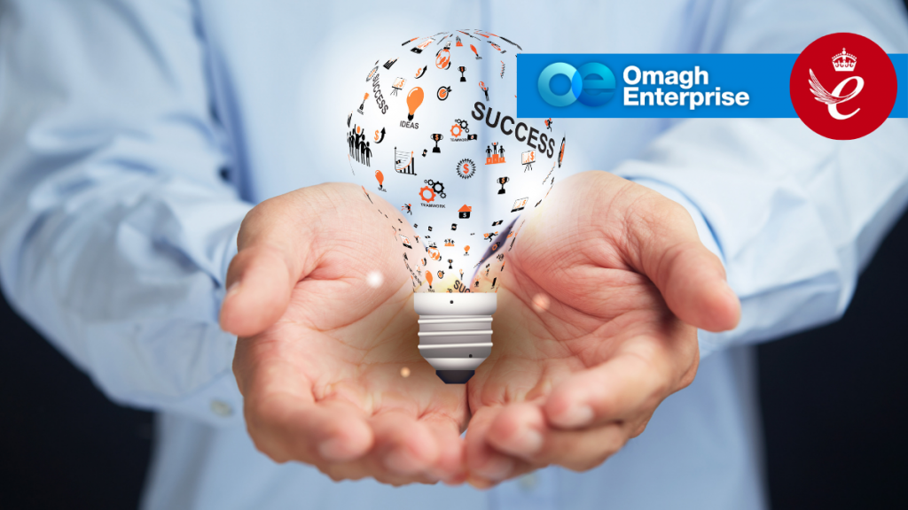 A person in a blue shirt holds a glowing lightbulb with icons and SUCCESS inside. The Omagh Enterprise logo and a Queen’s Award emblem are in the top right corner.