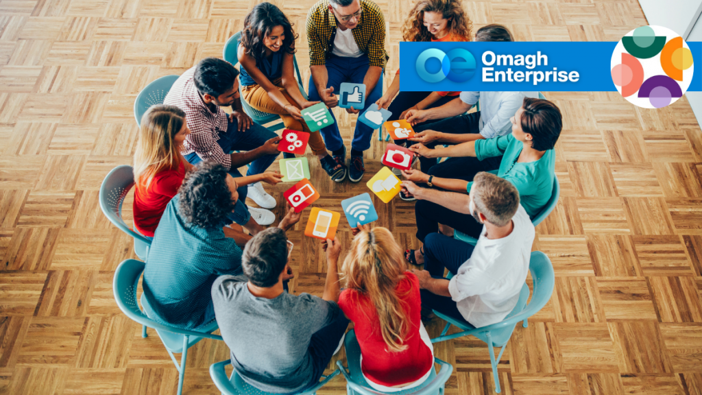 A group of people sitting in a circle hold icons of digital apps; Omagh Enterprise logo appears in the top right.