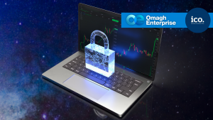 A digital padlock hologram appears above a laptop displaying financial charts, with Omagh Enterprise and ICO logos in the top right corner, set against a starry background.