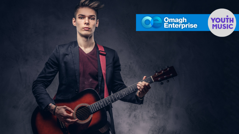 Young person playing an acoustic guitar, wearing a dark blazer and red shirt. Omagh Enterprise and Youth Music logos appear in the upper right corner.