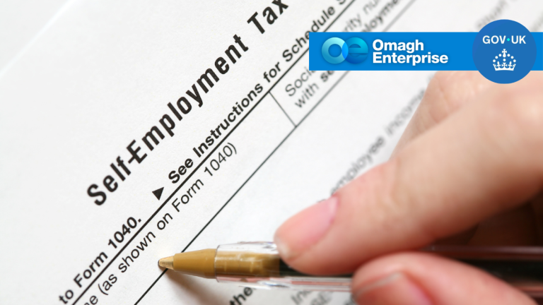 A hand holding a pen over a self-employment tax form with Omagh Enterprise and GOV.UK logos in the corner.